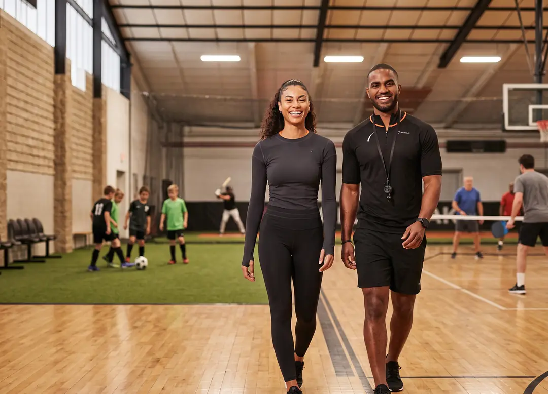Facility director and a coach walking a busy multi-sport facility with every space booked