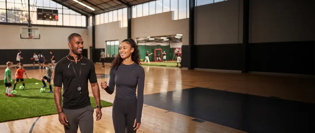 Facility director and a coach walking through a multi-sport complex during a youth clinic